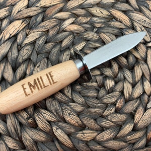 May include: A paring knife with a wooden handle and a stainless steel blade. The handle is engraved with the name "EMILIE".