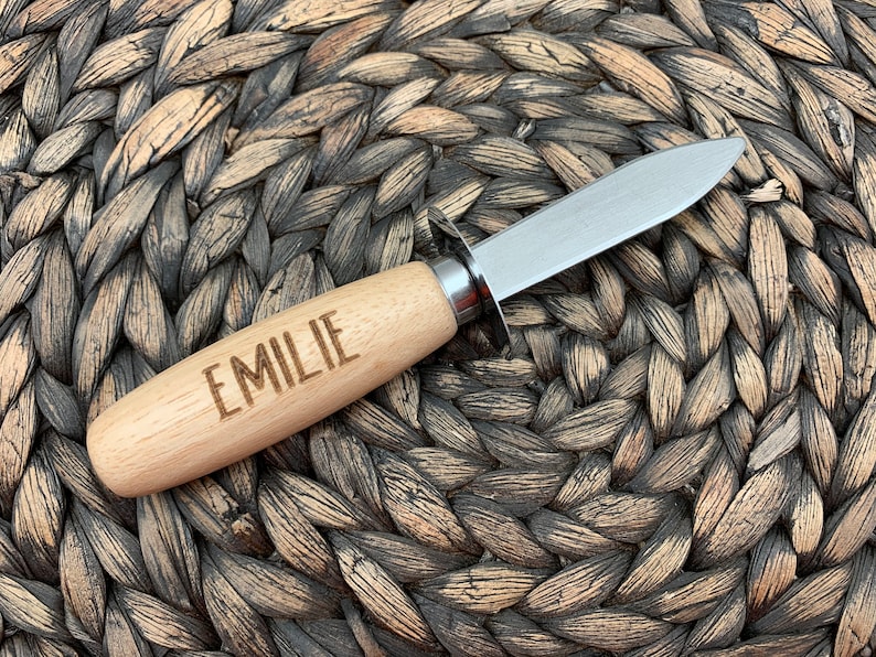 May include: A paring knife with a wooden handle and a stainless steel blade. The handle is engraved with the name "EMILIE".