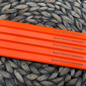 May include: Five orange carpenter pencils with black lettering that reads "Kevin Victory Construction" on each pencil.