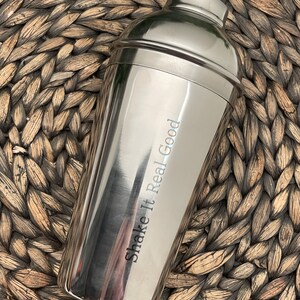 May include: A silver cocktail shaker with the text "Shake It Real Good" engraved on the side.