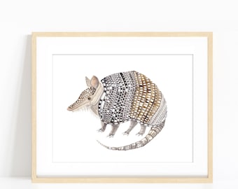 May include: Watercolor illustration of an armadillo in a wooden frame. The armadillo has a patterned shell in shades of brown, black, and white. The artwork is set against a white background, creating a clean and modern aesthetic.