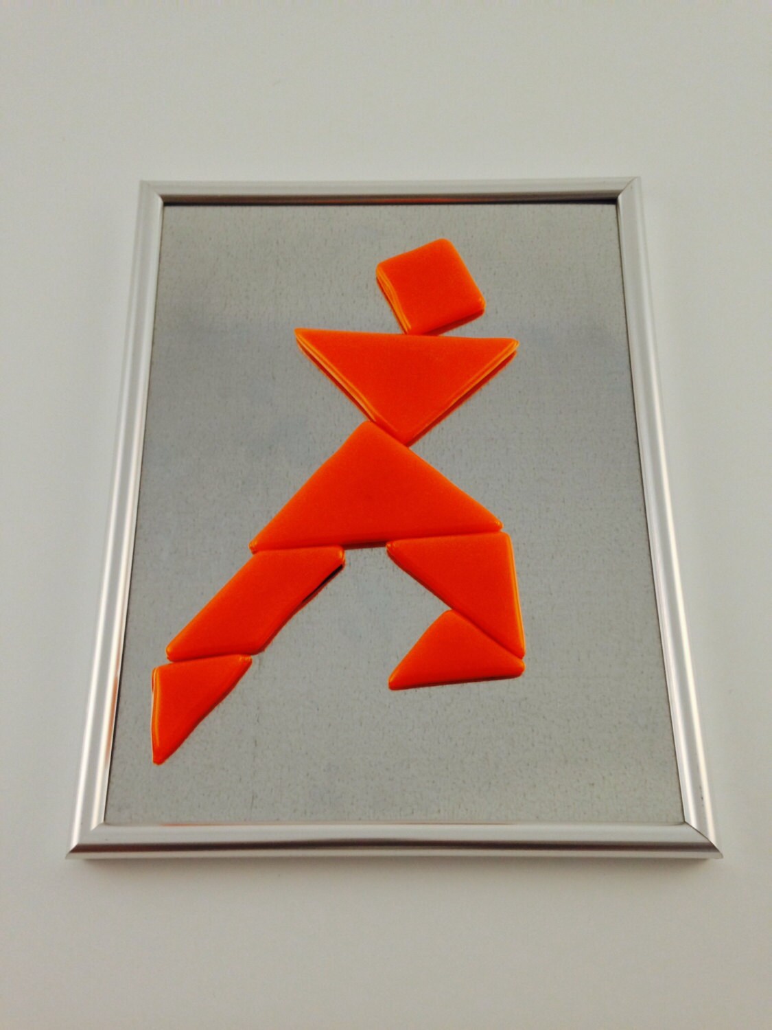 Tangram puzzle fused glass pieces in a variety of colors on silver frame