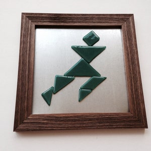 Tangram puzzle fused glass pieces in a variety of colors on brown frame