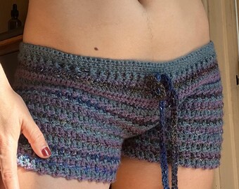 Könnte beinhalten: Blaue und lila gestreifte Häkelshorts mit einem Kordelzug. Die Shorts sind aus einem weichen, strukturierten Garn gefertigt.