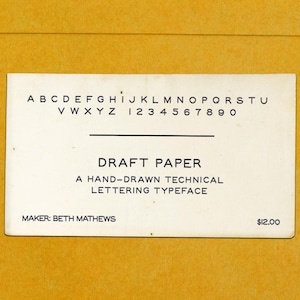 Peut inclure: Une carte rectangulaire blanche avec du texte noir présentant l'alphabet de A à U et V à Z, les chiffres 0 à 9, et le titre DRAFT PAPER A HAND-DRAWN TECHNICAL LETTERING TYPEFACE. La carte inclut le texte MAKER: BETH MATHEWS et 12,00 $.