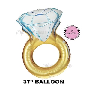 Op de afbeelding: Een grote gouden ringballon van 94 cm met een witte diamant erop. De ballon is gevormd als een verlovingsring.