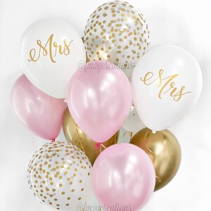 May include: A bouquet of balloons in pink, white, and gold. The balloons have gold confetti and the words "Mrs." written on them.