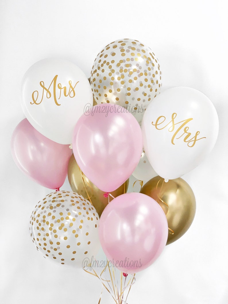 May include: A bouquet of balloons in pink, white, and gold. The balloons have gold confetti and the words "Mrs." written on them.