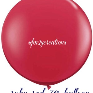 Puede incluir: Un gran globo rojo rub&iacute; de 91 cm de di&aacute;metro. El globo est&aacute; inflado y tiene un acabado brillante. El texto "@fm2ycreations" est&aacute; impreso en el globo.