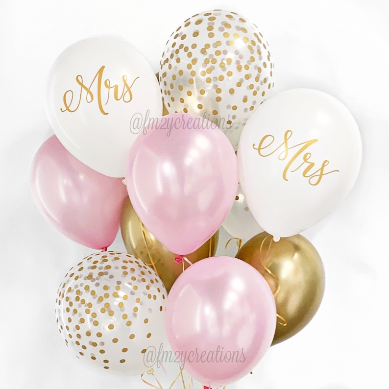 May include: A bouquet of pink and white balloons with gold confetti. The balloons have the word "Mrs." written on them in gold lettering.