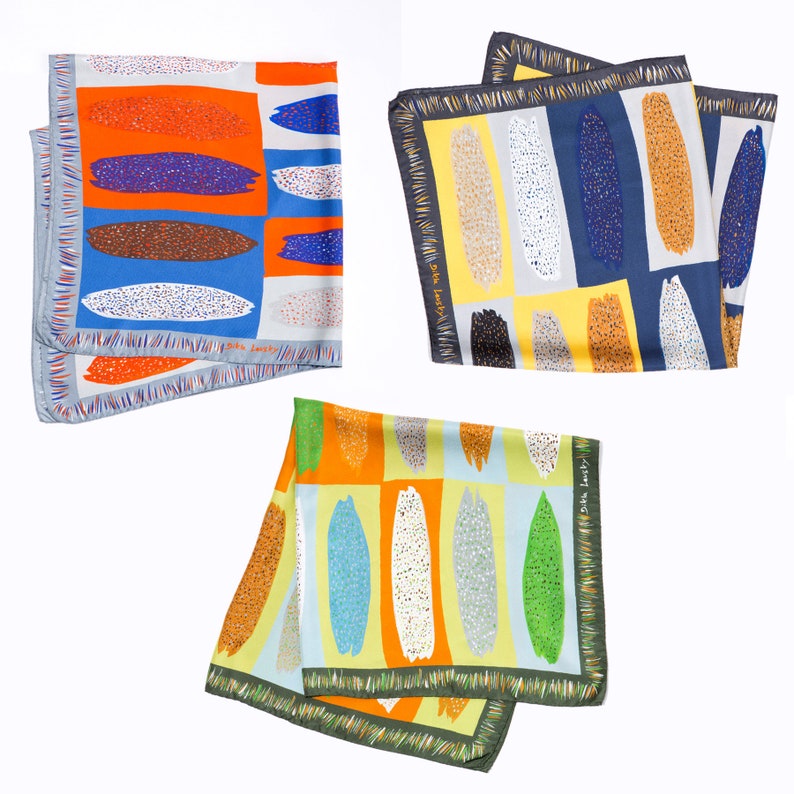 May include: Three colourful silk scarves with abstract patterns of brushstrokes and dots. The scarves are in shades of orange, blue, green, yellow, and white. The scarves have a fringed edge.