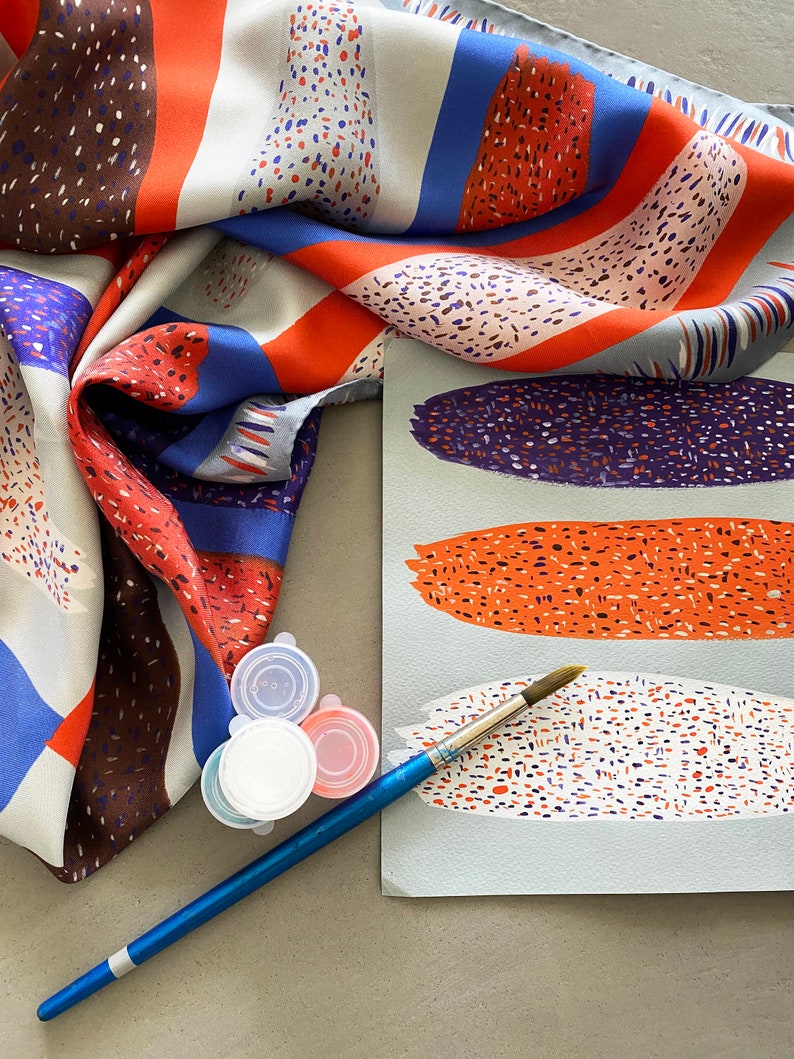May include: A blue, red and white patterned silk scarf with a paintbrush and three small containers of paint. The paint colours are white, red and blue.