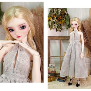 May include: A doll wearing a grey lace dress with a plunging neckline. The doll has long blonde hair and blue eyes.