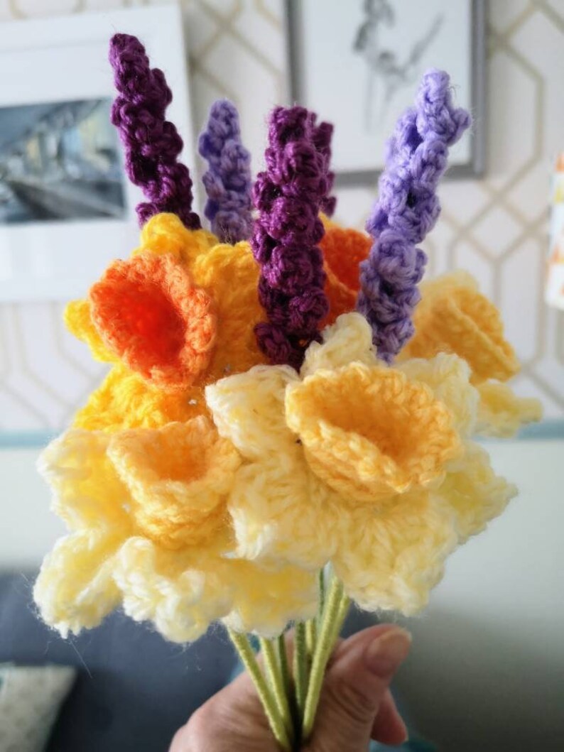 May include: A bouquet of crocheted flowers, including yellow daffodils and purple lavender.