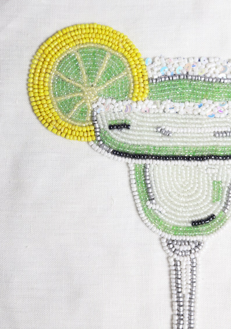 May include: A beaded margarita glass with a lime wedge, made with green, white, and silver beads.