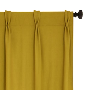 Puede incluir: Un par de cortinas de color amarillo mostaza con pliegues que cuelgan de una barra de cortina marrón.