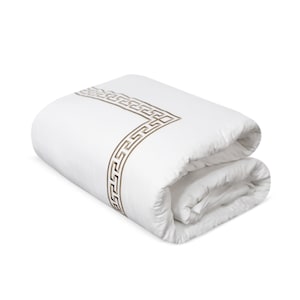 Op de afbeelding: Gevouwen witte dekbed met een decoratieve bruine Griekse sleutelrand. Het beddengoed is netjes opgevouwen en toont het gedetailleerde patroon. Het dekbed heeft een effen witte kleur, wat zorgt voor een strakke en elegante uitstraling.
