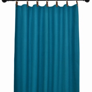 Puede incluir: Cortinas azul turquesa con pestañas de cuero marrón que cuelgan de una barra de metal negro.