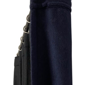 Puede incluir: Un juego de cortinas azul oscuro y negro colgadas de una barra de metal con anillos plateados. Las cortinas están hechas de una tela gruesa y texturizada.