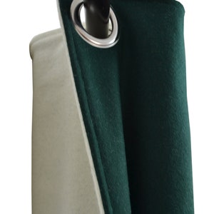 May include: A close-up of a green and white curtain with a silver grommet. The curtain is hanging from a black rod.