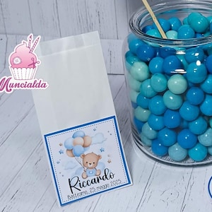 Può includere: Un barattolo di vetro pieno di caramelle blu, circondato da elementi decorativi per un baby shower. Include etichette con un disegno di orsetto, il nome "Riccardo" e la data "25 maggio 2025".