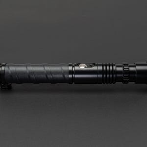 May include: A black lightsaber prop with a textured grip and a silver button. The lightsaber has a black metal barrel and a black plastic end cap.