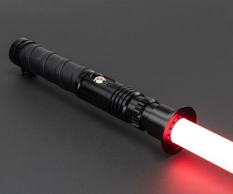 May include: A black lightsaber with a red blade. The lightsaber has a textured grip and a black emitter.