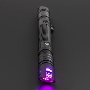 May include: A black lightsaber with a purple light saber blade. The lightsaber has a textured black handle with a button on the side.