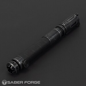 Pode incluir: Um sabre de luz preto com uma empunhadura texturizada e detalhes met&aacute;licos. O punho apresenta detalhes intrincados e um design futurista. O logotipo Saber Forge &eacute; vis&iacute;vel na base. Ideal para cosplay ou exibi&ccedil;&atilde;o.