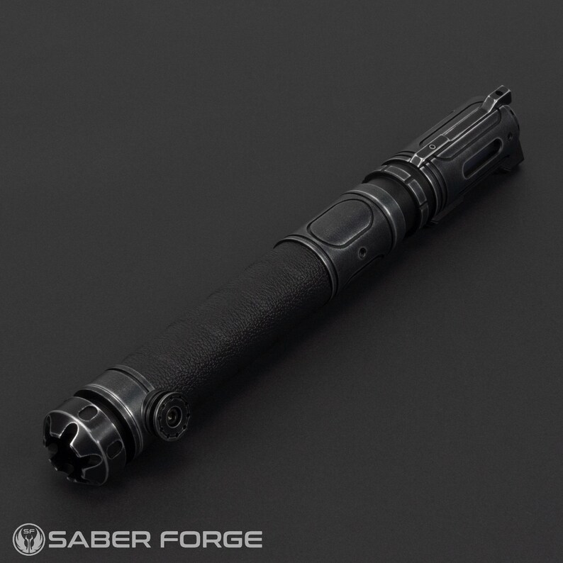 Pode incluir: Um sabre de luz preto com uma empunhadura texturizada e detalhes met&aacute;licos. O punho apresenta detalhes intrincados e um design futurista. O logotipo Saber Forge &eacute; vis&iacute;vel na base. Ideal para cosplay ou exibi&ccedil;&atilde;o.