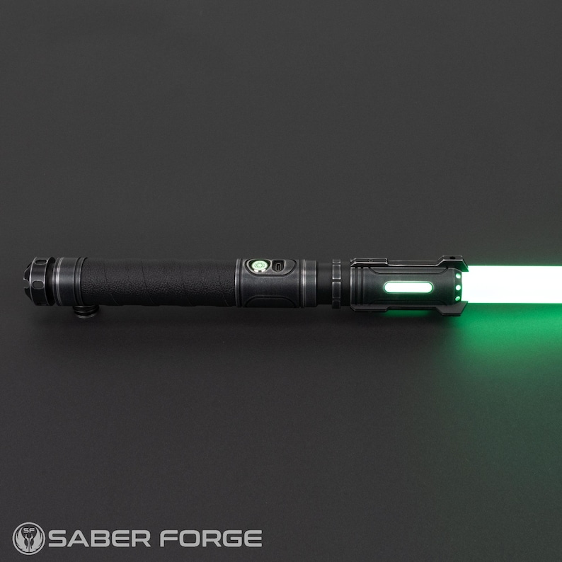 Pode incluir: Um sabre de luz preto e prateado com uma l&acirc;mina verde brilhante. O punho tem uma pega texturizada e v&aacute;rios detalhes prateados. O sabre de luz est&aacute; iluminado, com o texto "SABER FORGE" na parte inferior.