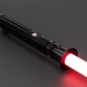 Op de afbeelding: Een zwart lightsaber met een rode blade. De lightsaber heeft een getextureerde handgreep en een zwarte emitter.