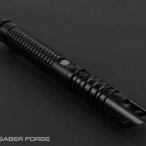 May include: A black lightsaber with a ribbed handle and a detailed emitter. The lightsaber has a button with a logo and is set against a dark background. The Saber Forge logo is visible at the bottom.