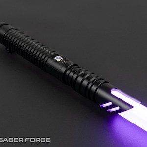 May include: A black lightsaber with a ribbed handle and a glowing purple blade. The lightsaber has a sleek design with a button and a logo that says "Saber Forge" at the bottom.