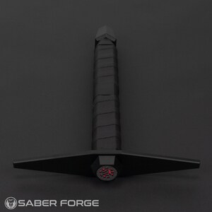 May include: A black lightsaber with a red, triangular, glowing blade tip. The lightsaber has a black handle with a textured grip.
