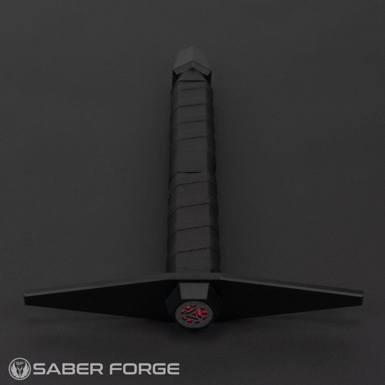 May include: A black lightsaber with a red, triangular, glowing blade tip. The lightsaber has a black handle with a textured grip.