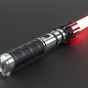 May include: A silver and black lightsaber with a red blade. The lightsaber has a textured black grip and a silver emitter with a red button.