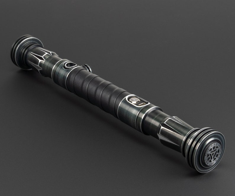 Pode incluir: Um sabre de luz preto e prateado com uma pega texturizada e um bot&atilde;o prateado. O sabre de luz tem um emissor preto e prateado e uma empunhadura preta e prateada.