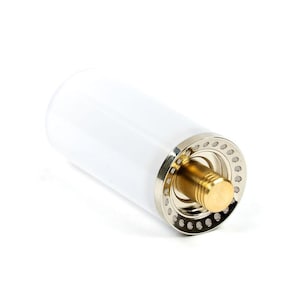 Puede incluir: Un tubo de plástico transparente con una tapa roscada de plata y oro. La tapa tiene un anillo decorativo con pequeños agujeros alrededor del borde.