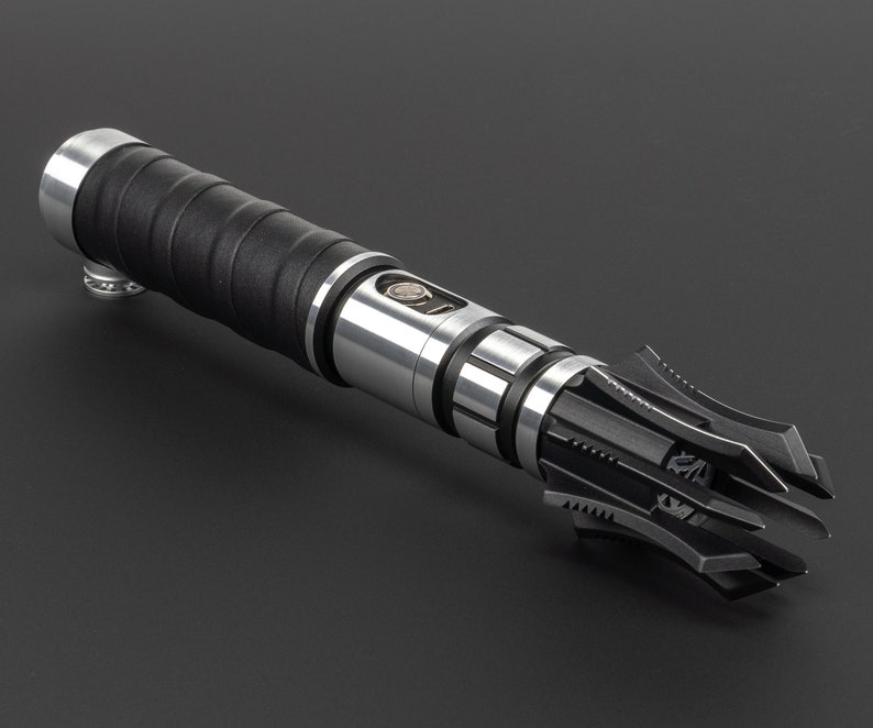 May include: A black and silver lightsaber with a detailed, intricate, and sharp-edged hilt.