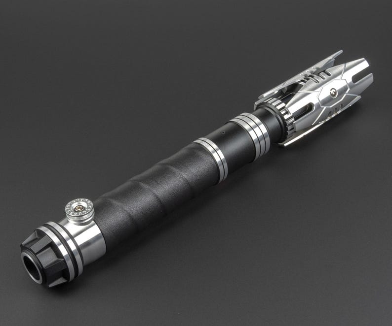 May include: A silver and black lightsaber with a textured black handle and a silver emitter with a detailed design.