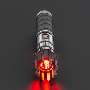 May include: A black and silver lightsaber with a red blade. The lightsaber has a detailed design with a black handle and a silver emitter.
