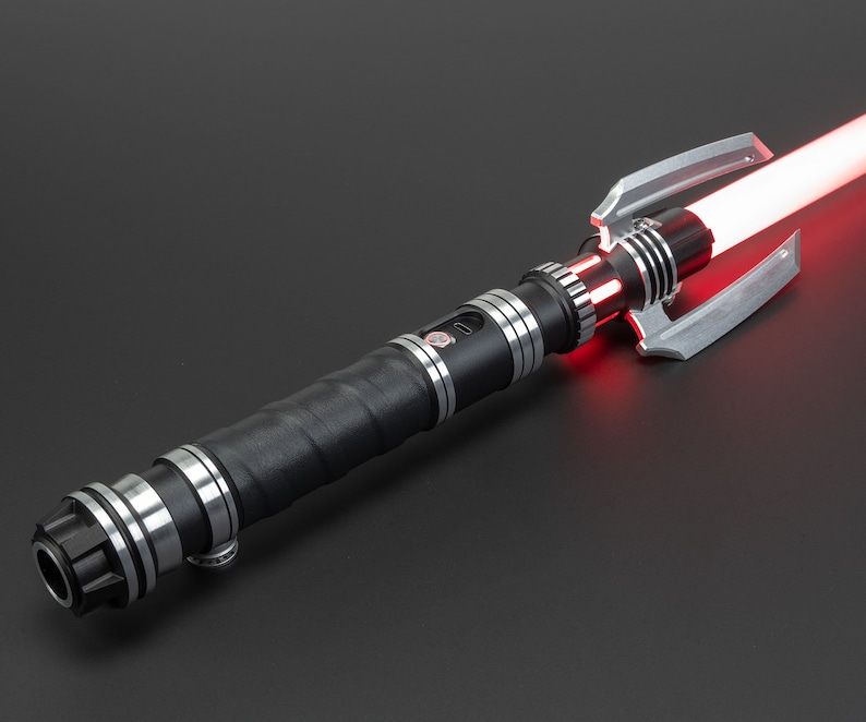 May include: A black lightsaber with a silver hilt and a red blade. The hilt has a textured grip and a silver emitter.