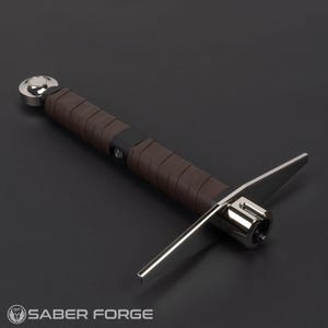 May include: A lightsaber hilt featuring a brown leather-wrapped grip, a polished silver pommel, and a crossguard with two extended silver metal quillons. The hilt includes a black control box section with a circular button and a silver emitter.