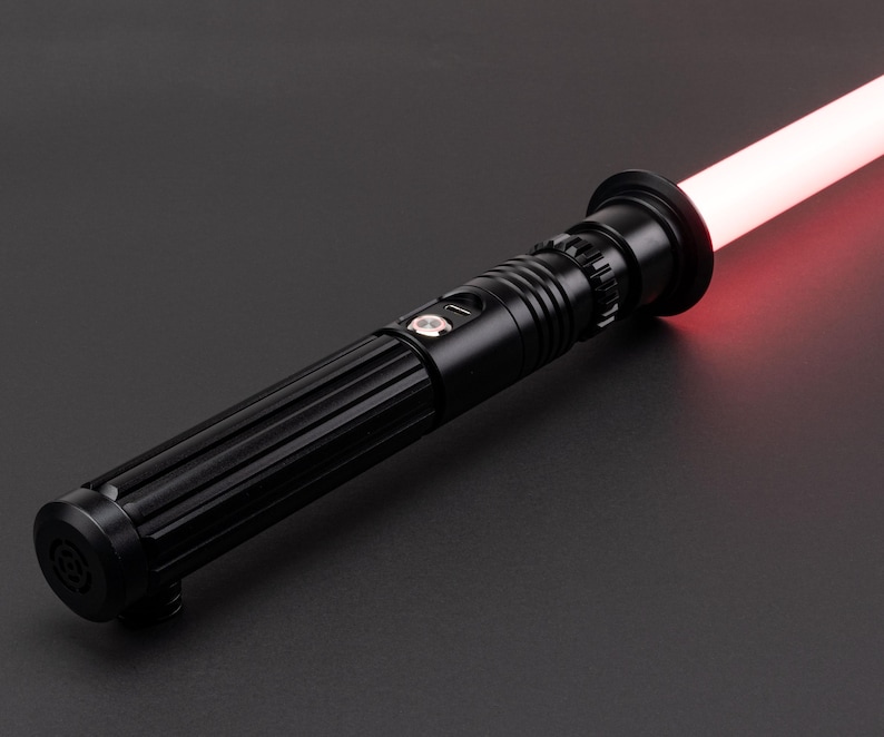 Op de afbeelding: Een zwart lightsaber met een rode blade. De lightsaber heeft een getextureerde handgreep en een zilveren knop.