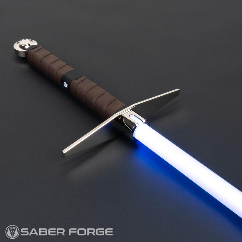 May include: A lightsaber with a glowing blue blade, a silver crossguard, and a brown leather-wrapped hilt. The pommel is silver, and the hilt features a black activation switch with a circular icon. The text SABER FORGE is visible at the bottom.