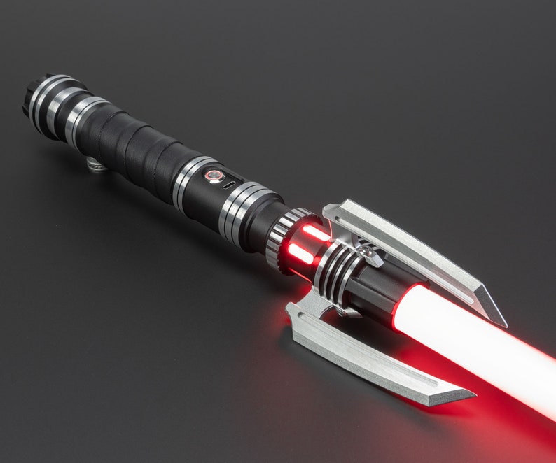 May include: A black lightsaber with a red blade and a silver handle. The lightsaber has a unique design with a claw-like emitter.