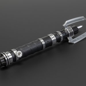 May include: A black and silver lightsaber with a unique, three-pronged blade design. The lightsaber has a textured grip and a silver knob.