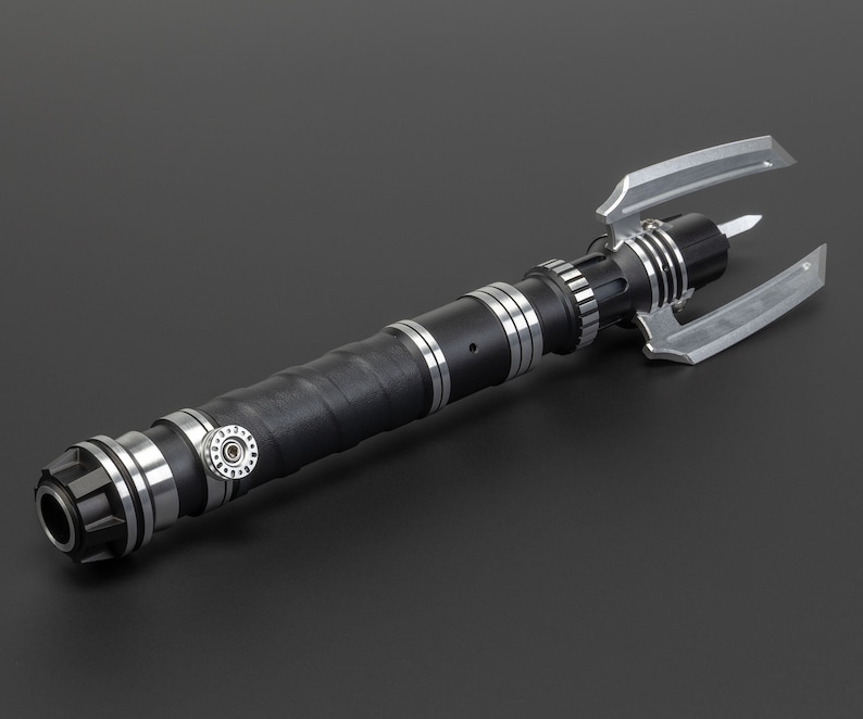 May include: A black and silver lightsaber with a unique, three-pronged blade design. The lightsaber has a textured grip and a silver knob.