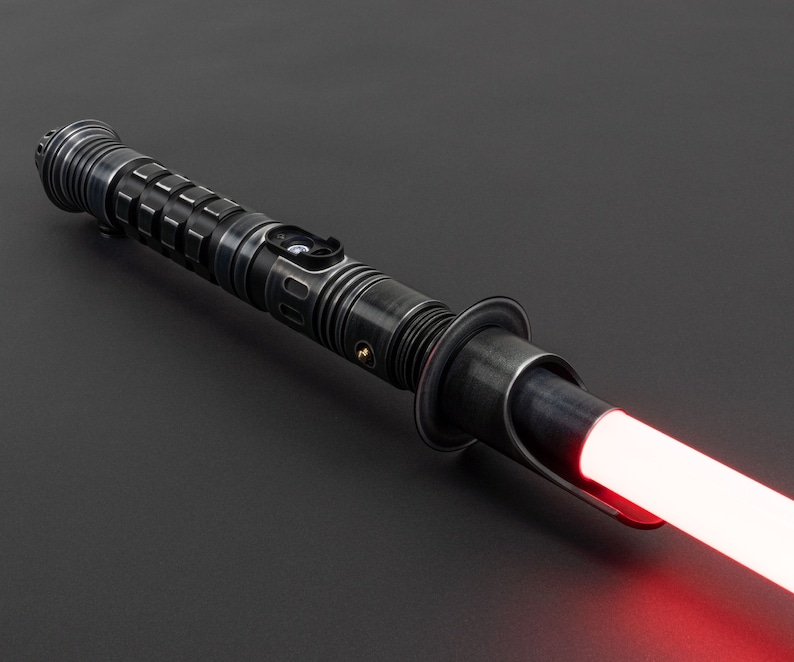 K&ouml;nnte beinhalten: Ein schwarzes Lichtschwert mit einer roten Klinge. Das Lichtschwert hat einen strukturierten Metallgriff mit einem silbernen Knopf.